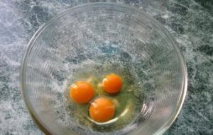 Разбитые куриные яйца в удобной посуде для взбивания