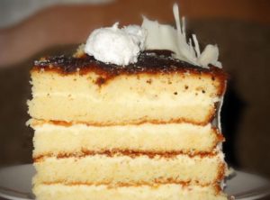 Кусочек готового золотистого торта на основе масляного бисквита с белым шоколадом